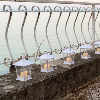 Lanternes blanches avec bougies led le long d'un muret au bord du Lac de Garde